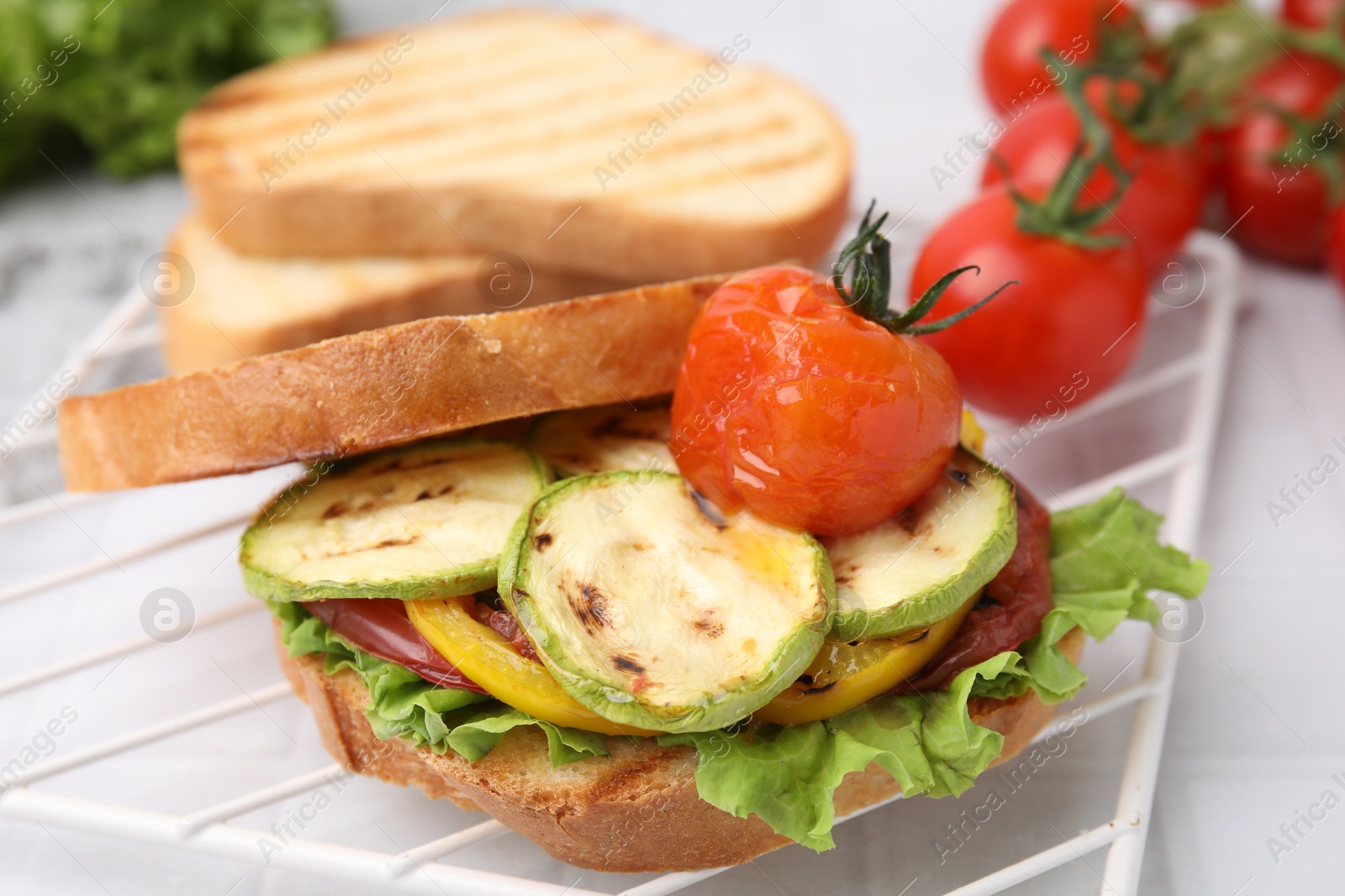 Photo of Tasty sandwich with grilled vegetables on white tiled table, closeup