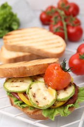 Photo of Tasty sandwich with grilled vegetables on white tiled table, closeup