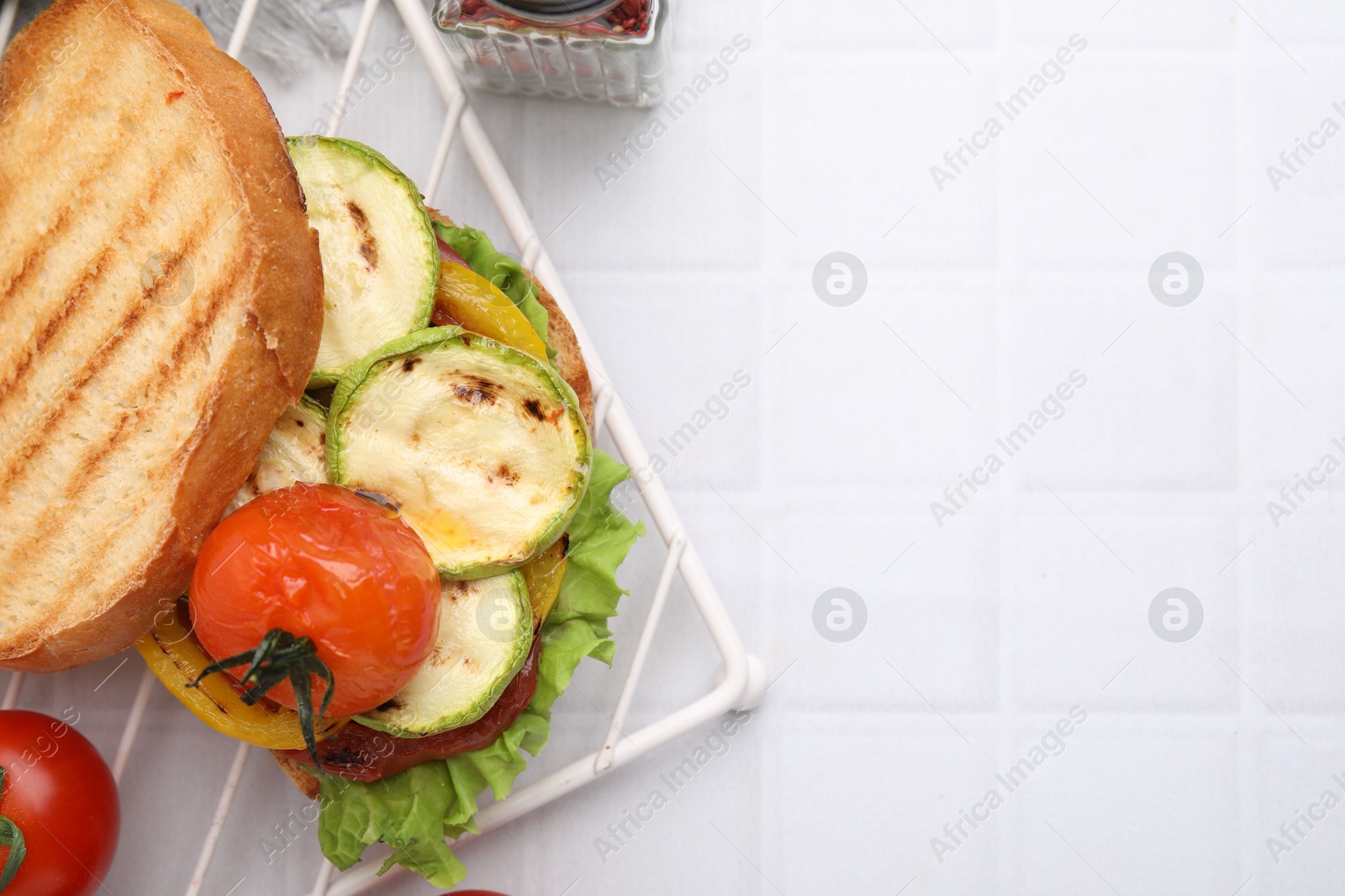 Photo of Tasty sandwich with grilled vegetables on white tiled table, flat lay. Space for text