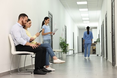 Photo of Patients waiting for appointment and doctor in hospital hallway, selective focus