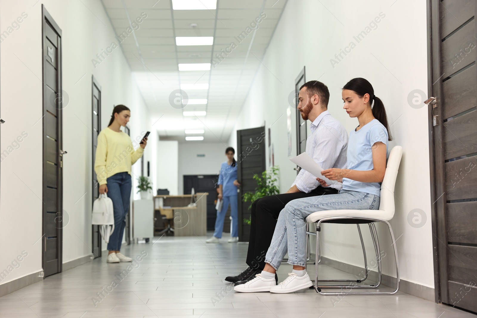 Photo of Patients waiting for appointment and doctor in hospital hallway, selective focus