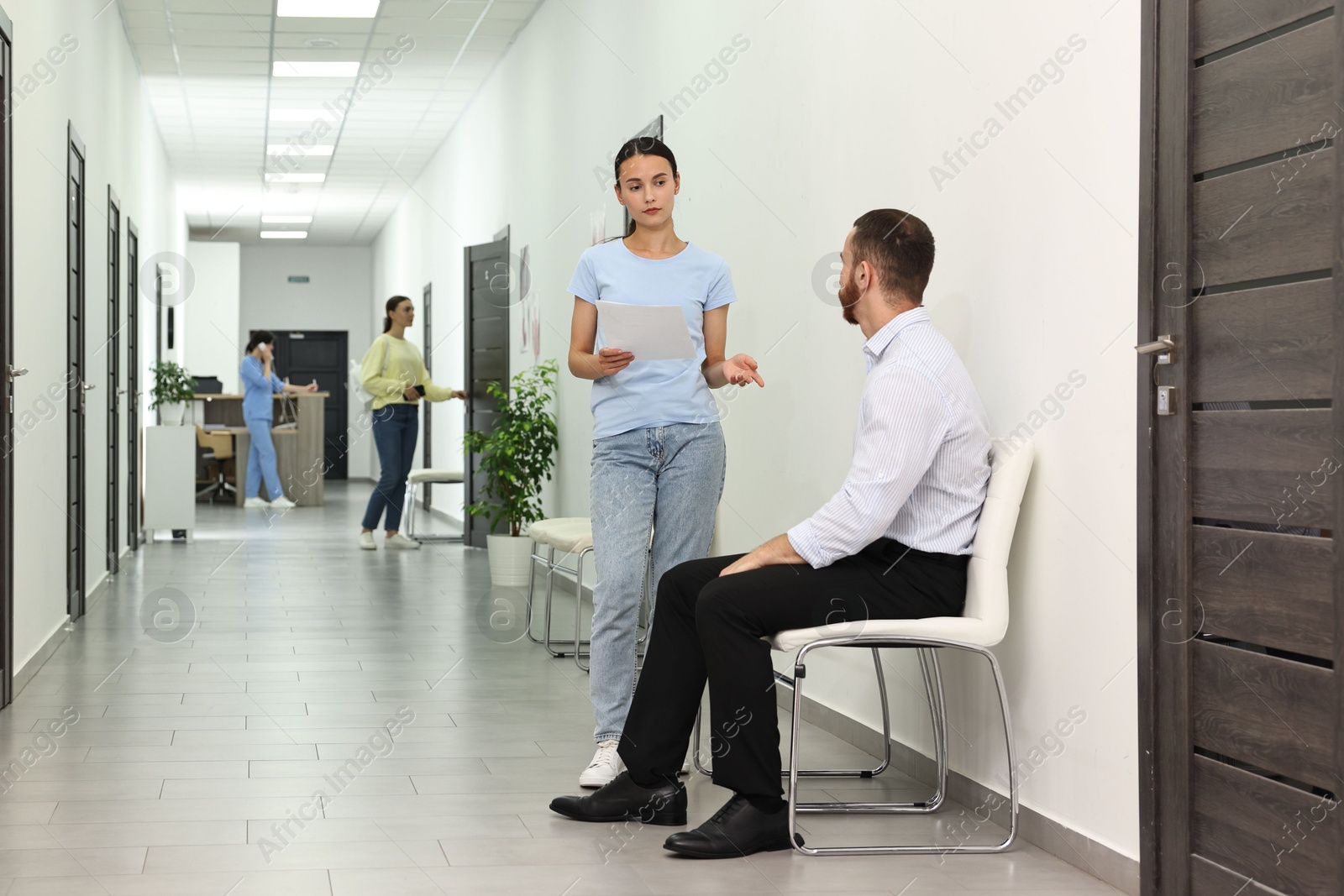 Photo of Patients waiting for appointment and doctor in hospital hallway, selective focus