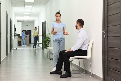 Patients waiting for appointment and doctor in hospital hallway, selective focus