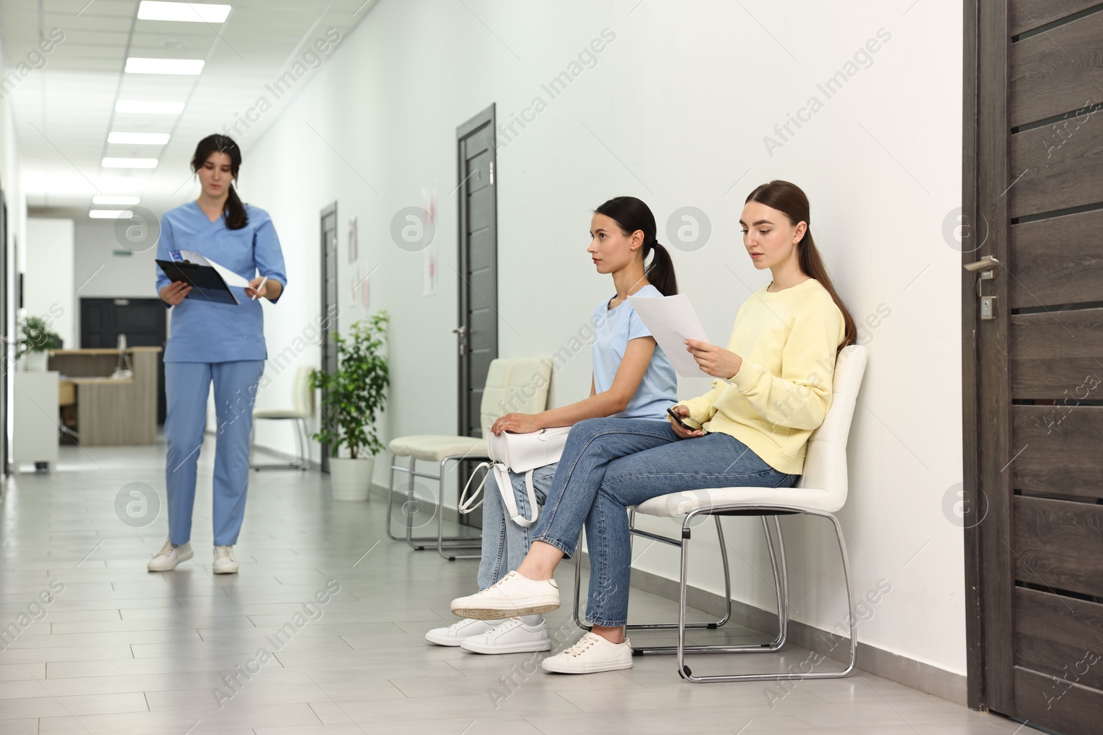 Photo of Patients waiting for appointment and doctor in hospital hallway, selective focus