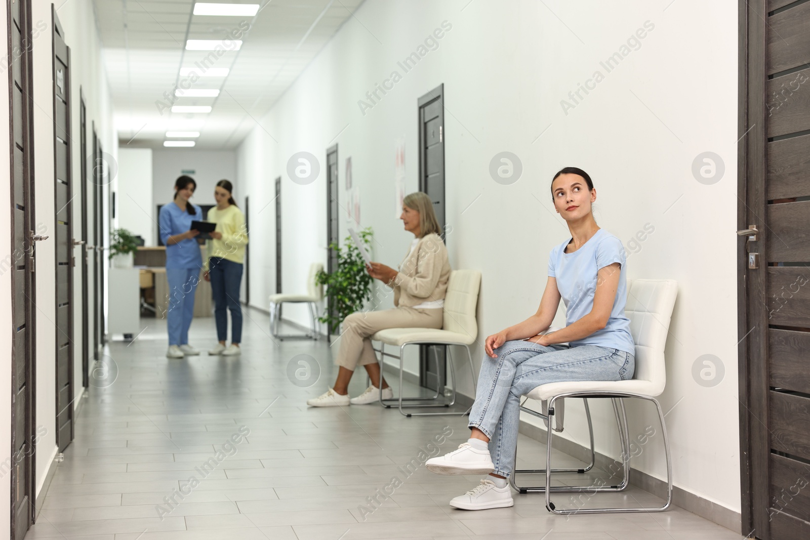 Photo of Patients waiting for appointment and doctor in hospital hallway, selective focus