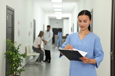 Nurse with clipboard in hospital hallway, selective focus