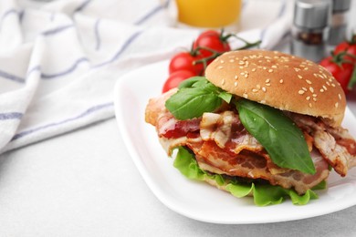 Delicious burger with bacon and greens on light table, closeup. Space for text