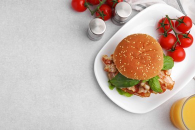 Photo of Delicious burger with bacon, greens, tomatoes and juice on light table, flat lay. Space for text