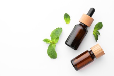 Photo of Bottles of essential oils and mint isolated on white, top view