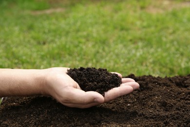 Photo of Woman holding pile of soil outdoors, closeup. Space for text