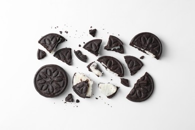 Photo of Whole and broken tasty sandwich cookies on white background, flat lay