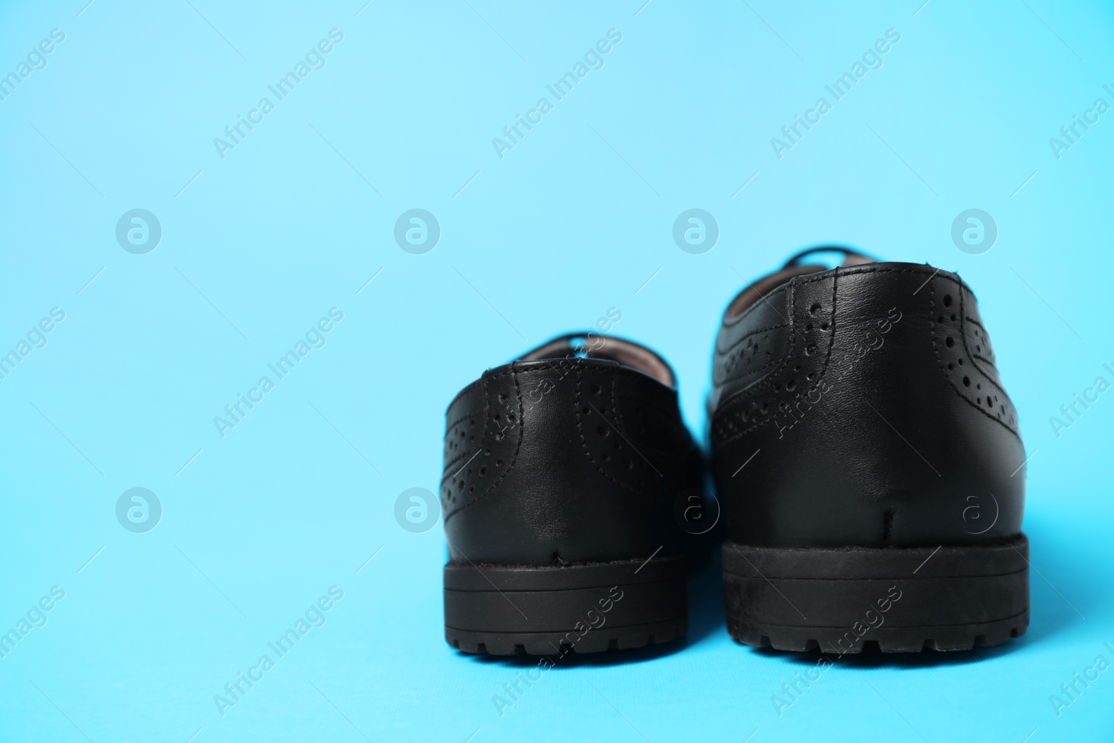 Photo of Big and small shoes on light blue background, space for text