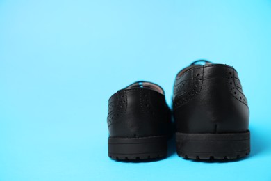 Photo of Big and small shoes on light blue background, space for text