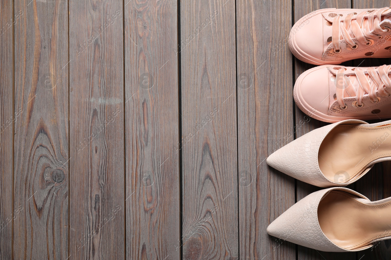 Photo of Big and small shoes on wooden table, top view. Space for text