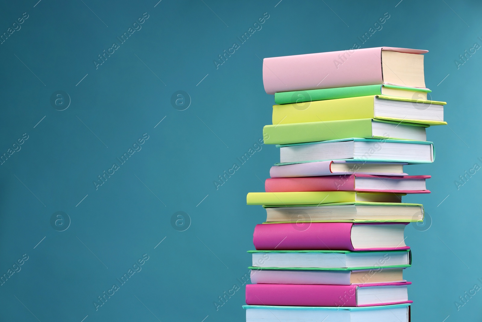 Photo of Stack of colorful books on light blue background, space for text