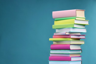 Stack of colorful books on light blue background, space for text