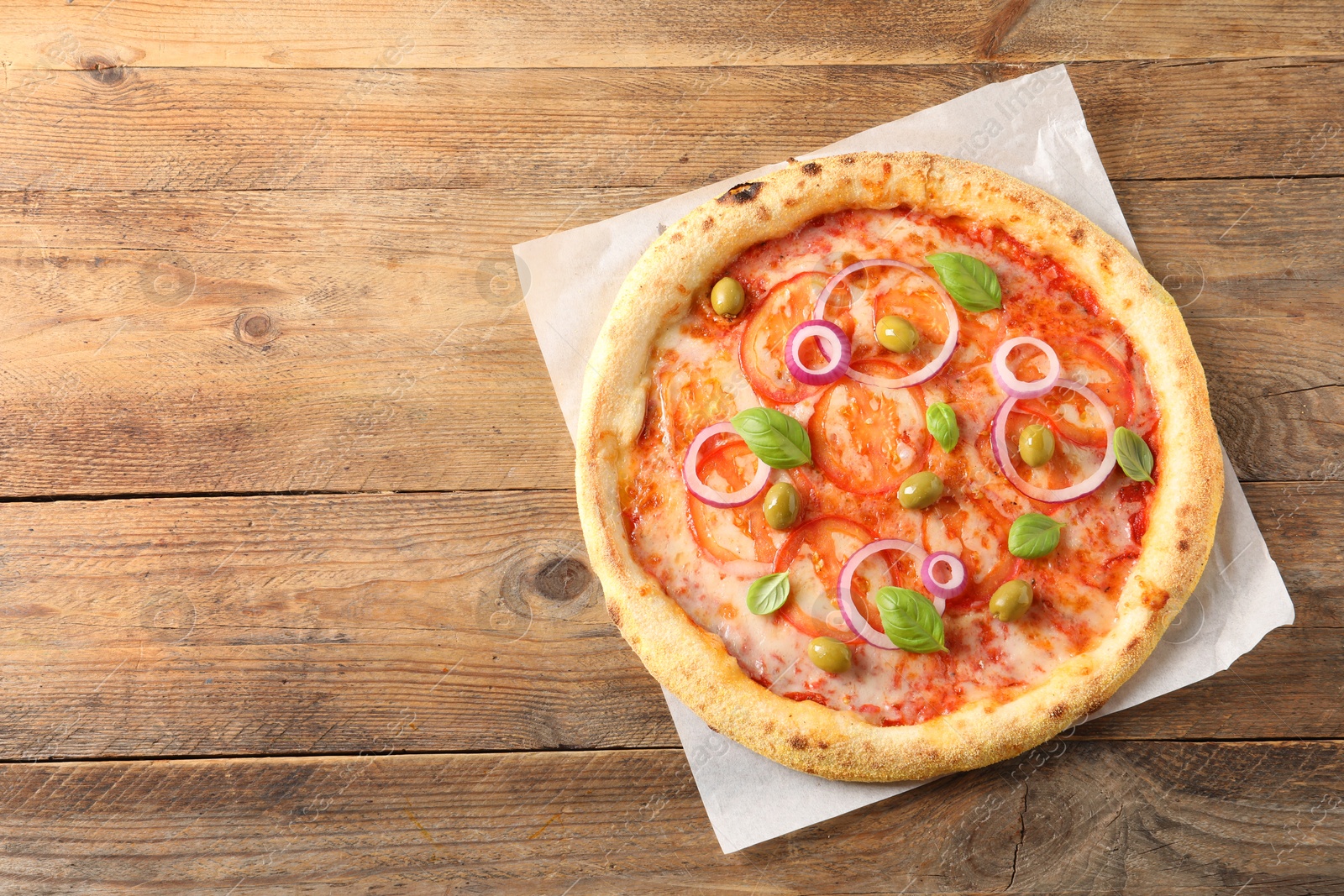 Photo of Delicious vegetarian pizza on wooden table, top view. Space for text