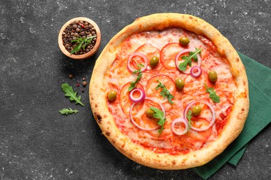 Photo of Delicious vegetarian pizza with arugula and peppercorns on black table, top view