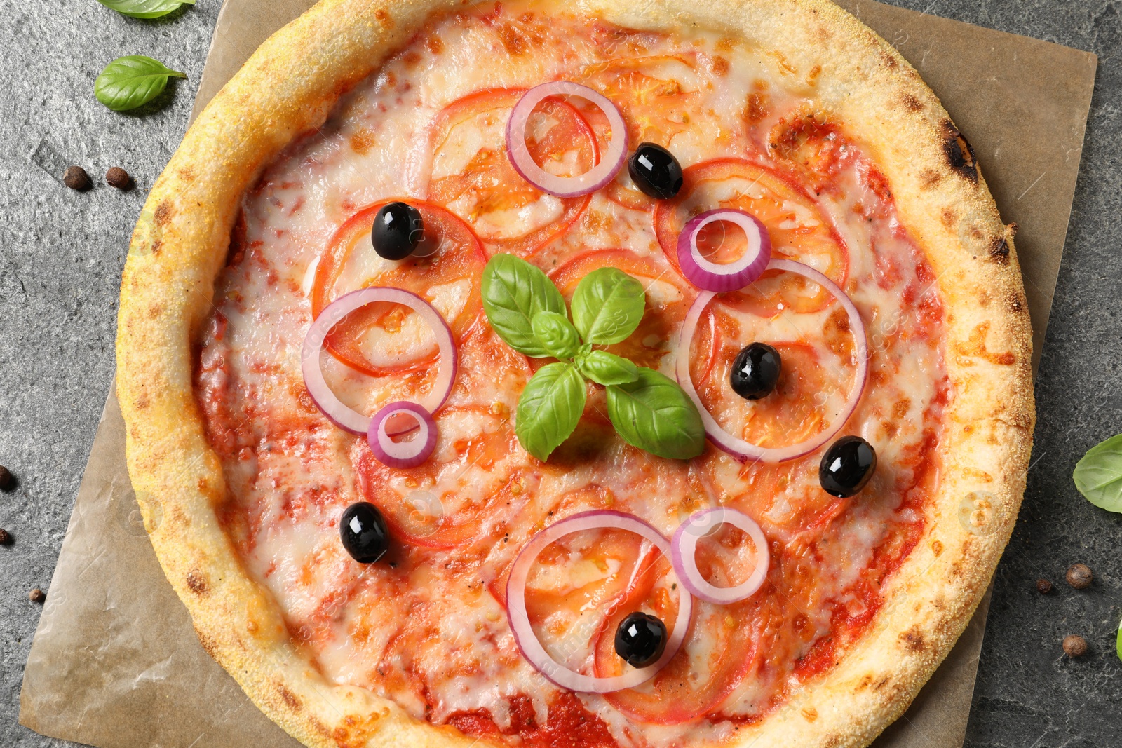 Photo of Delicious vegetarian pizza with basil and peppercorns on grey table, top view