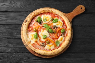 Photo of Delicious vegetarian pizza on black wooden table, top view