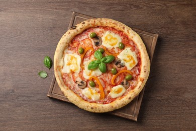 Photo of Delicious vegetarian pizza on wooden table, top view