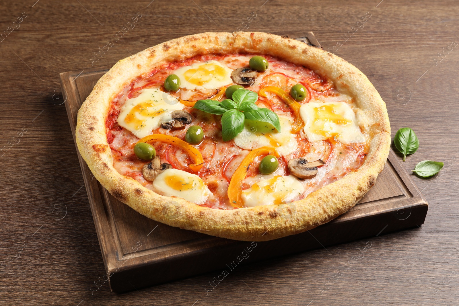 Photo of Delicious vegetarian pizza with fresh basil on wooden table