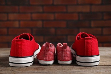 Photo of Big and small sneakers on wooden surface