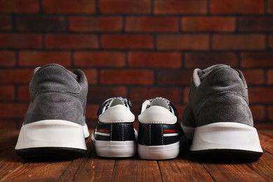 Photo of Big and small sneakers on wooden surface