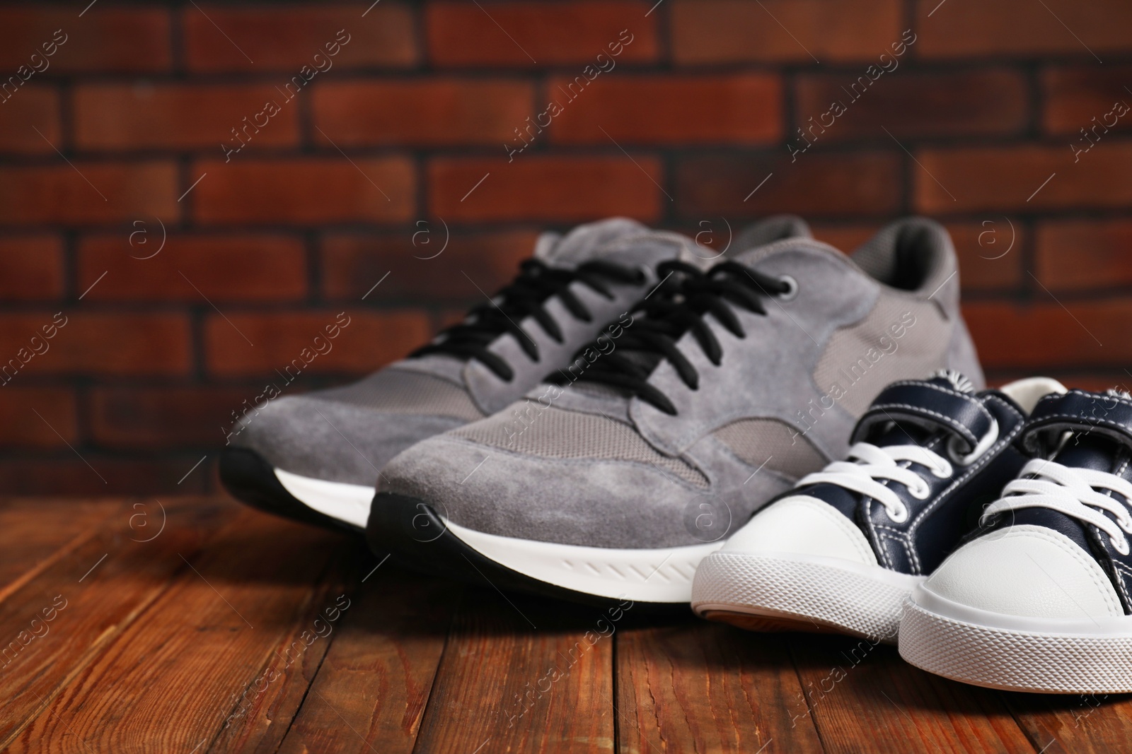 Photo of Big and small sneakers on wooden surface