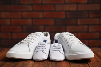 Photo of Big and small sneakers on wooden surface