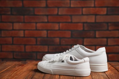 Photo of Big and small sneakers on wooden surface, space for text