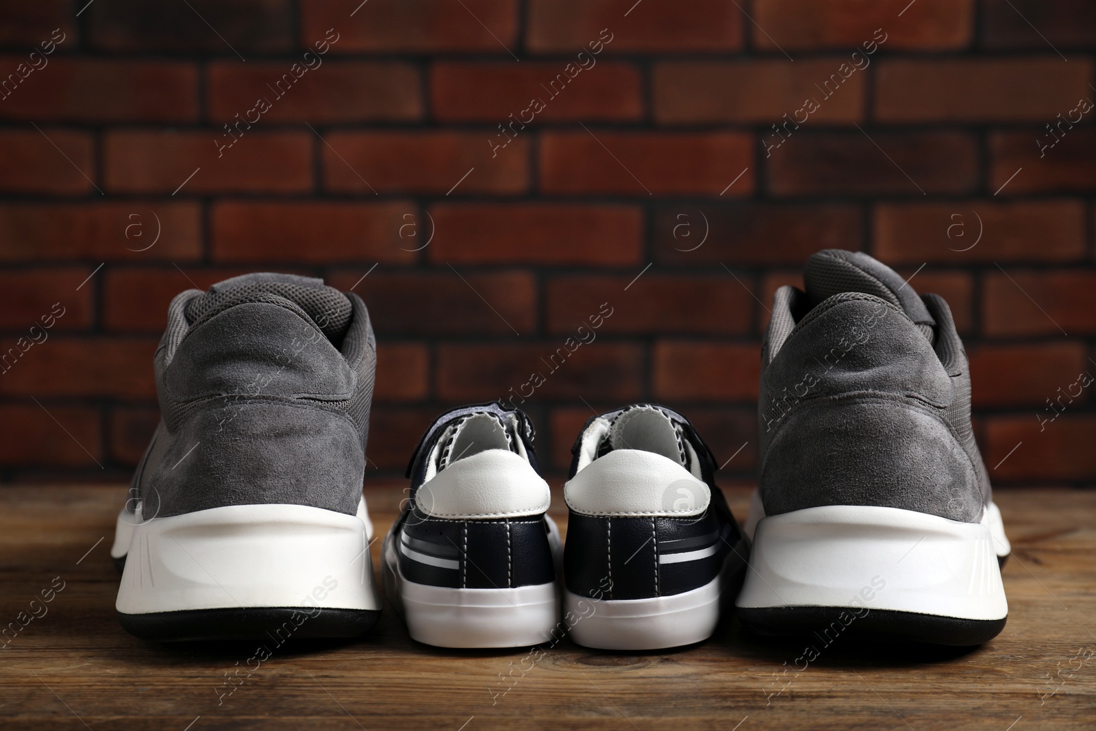 Photo of Big and small sneakers on wooden surface