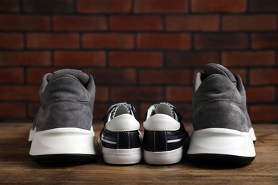 Photo of Big and small sneakers on wooden surface