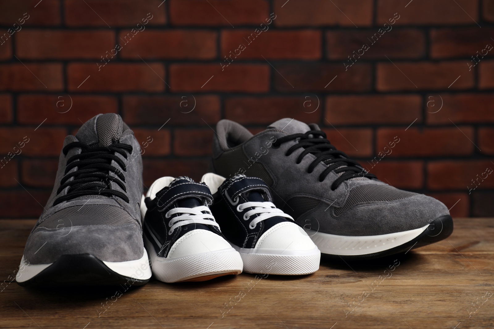 Photo of Big and small sneakers on wooden surface