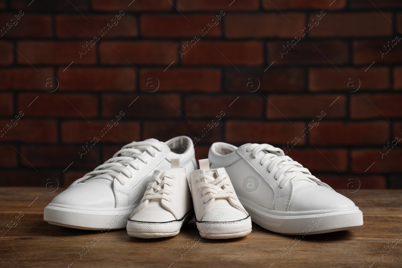 Photo of Big and small sneakers on wooden surface