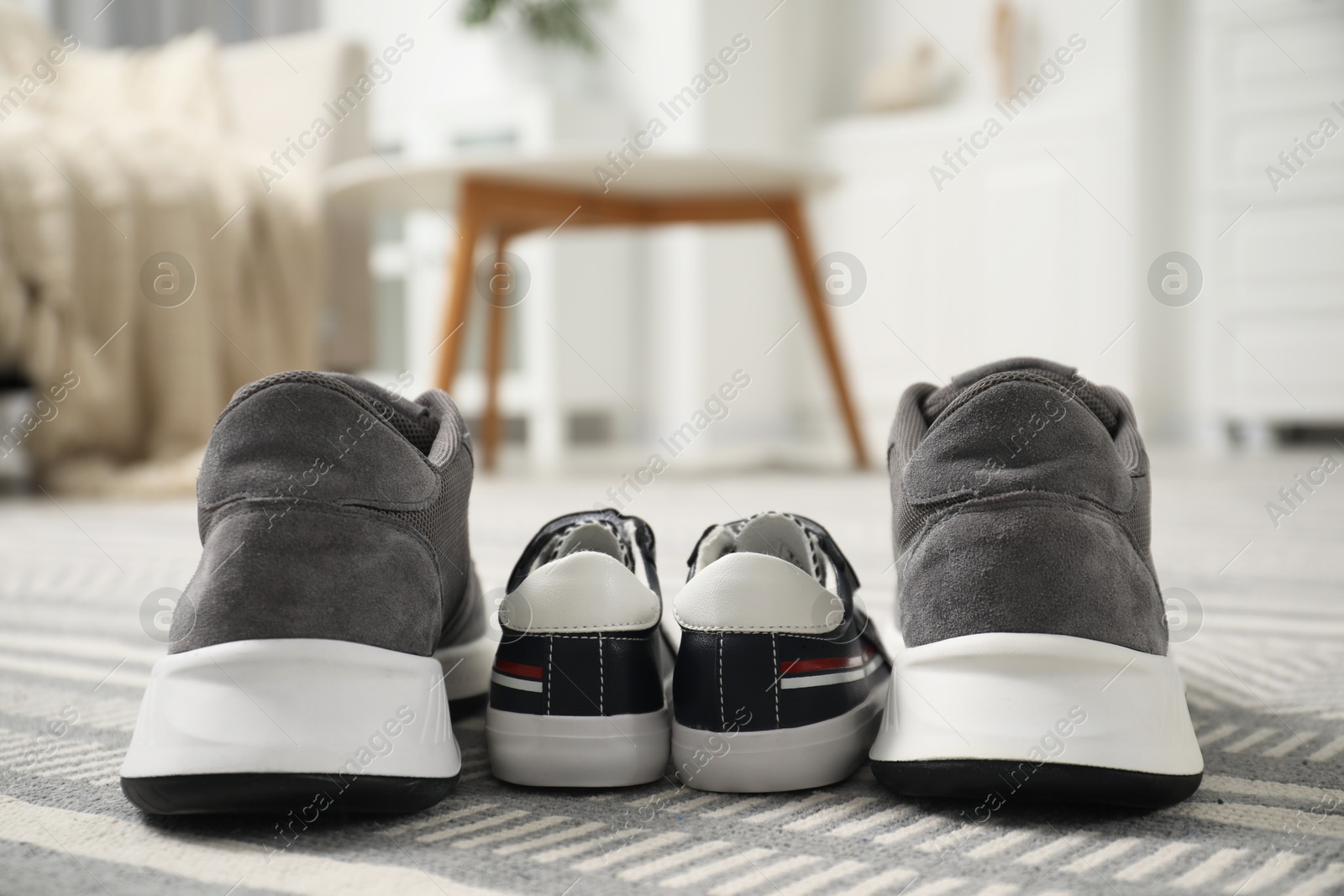 Photo of Big and small sneakers on carpet indoors