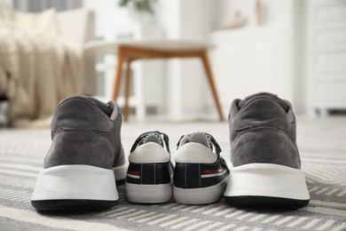 Photo of Big and small sneakers on carpet indoors