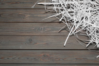 Photo of Shredded paper strips on wooden table, top view. Space for text