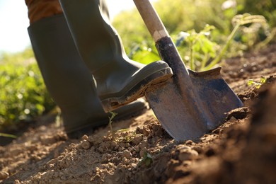 Farmer digging soil with shovel on sunny day, closeup