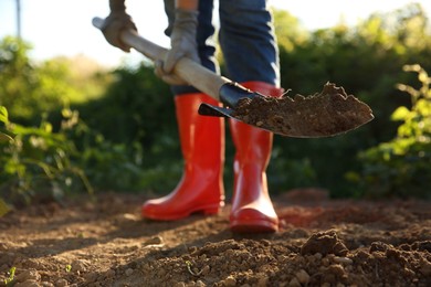 Farmer digging soil with shovel on sunny day, closeup