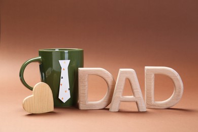 Photo of Happy Father's Day. Coffee in cup and word Dad made of wooden letters on brown background