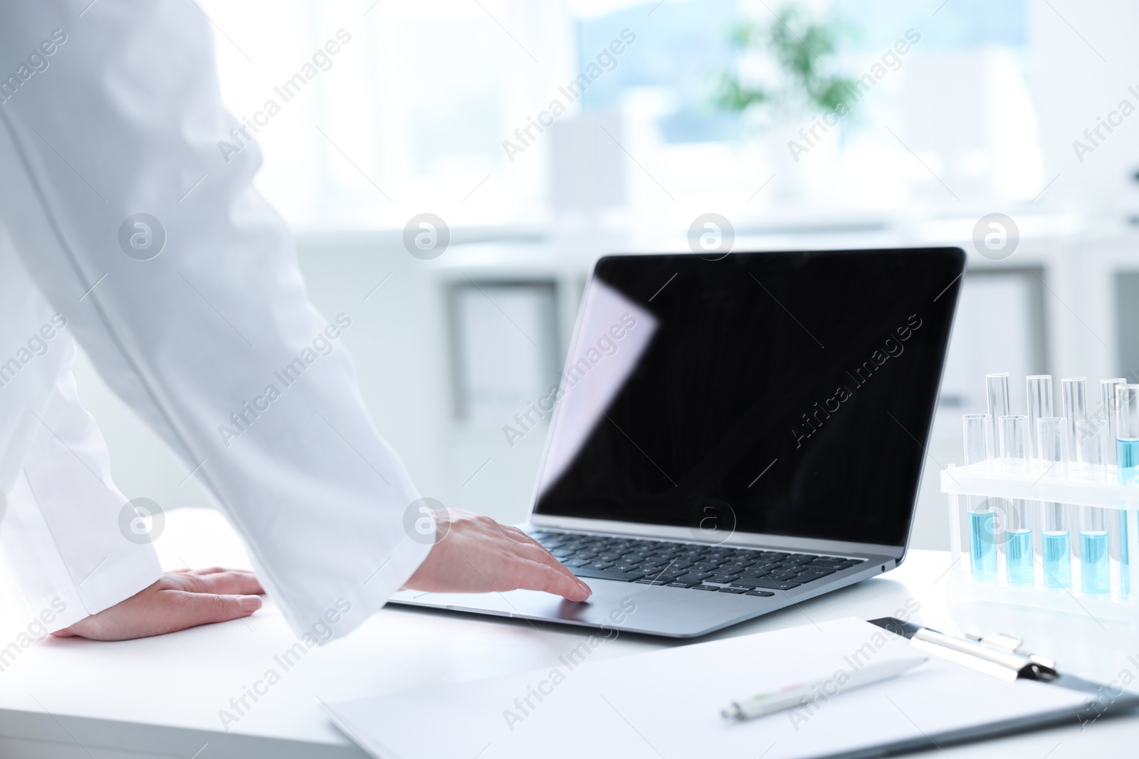 Photo of Doctor with laptop at table in clinic, closeup view