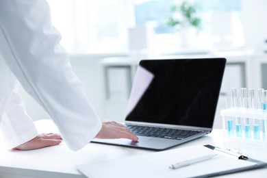 Doctor with laptop at table in clinic, closeup view