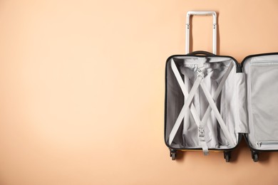 Photo of Open empty suitcase on beige background, top view. Space for text