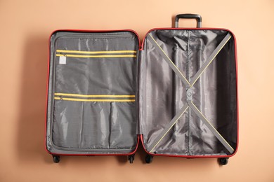 Photo of Open empty suitcase for travelling on beige background, top view