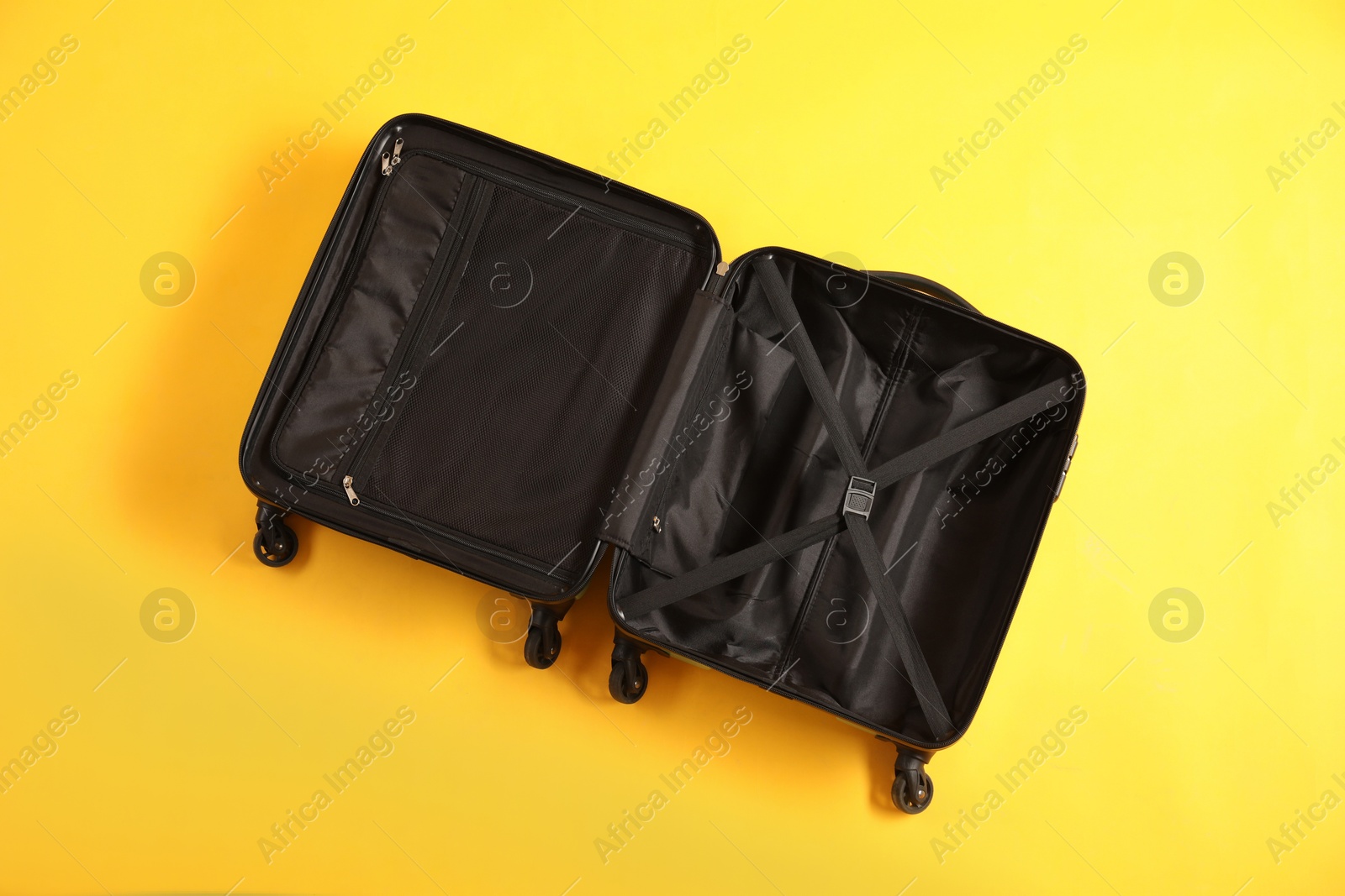 Photo of Open empty suitcase for travelling on yellow background, top view