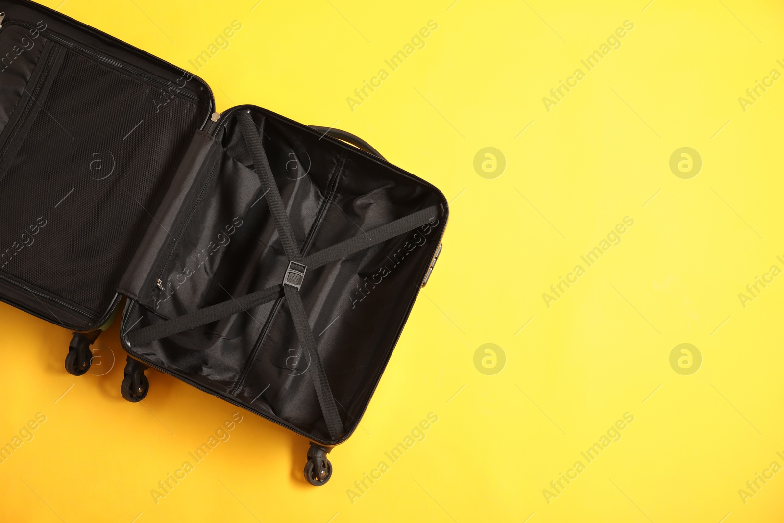 Photo of Open empty suitcase on yellow background, top view. Space for text