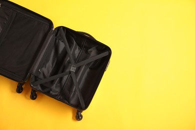 Photo of Open empty suitcase on yellow background, top view. Space for text