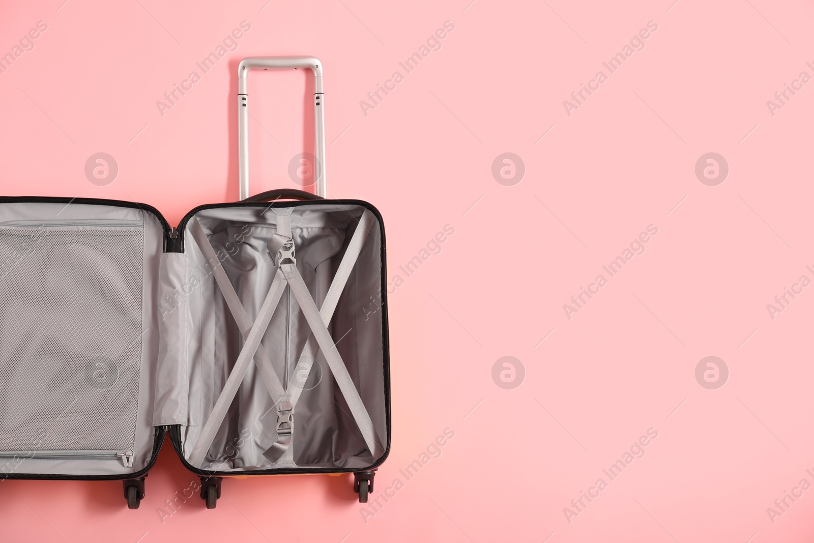 Photo of Open empty suitcase on pink background, top view. Space for text