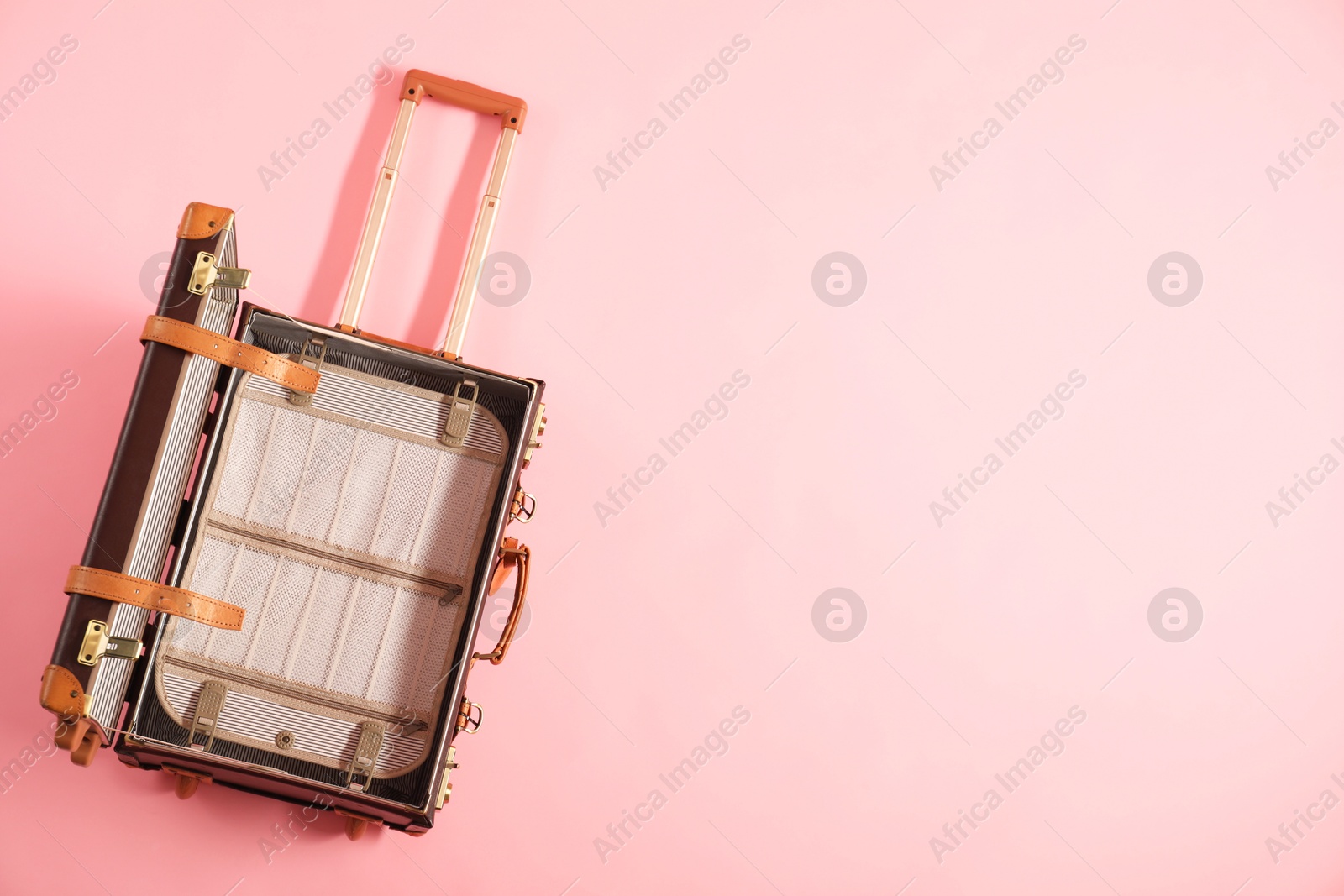 Photo of Open empty suitcase on pink background, top view. Space for text